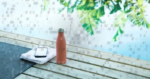 Peach insulated bottle standing on dock next to towel and smartphone with binary overlay