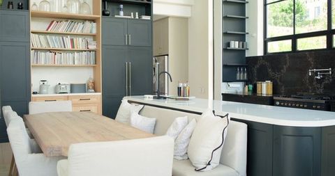 Rustic wooden dining table anchoring open-plan kitchen with white island and black faucet