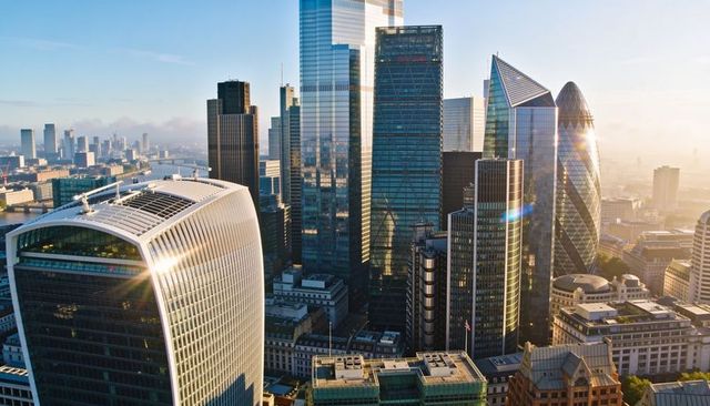 Sunlit london skyline featuring modern glass skyscrapers reflecting light and lens flare