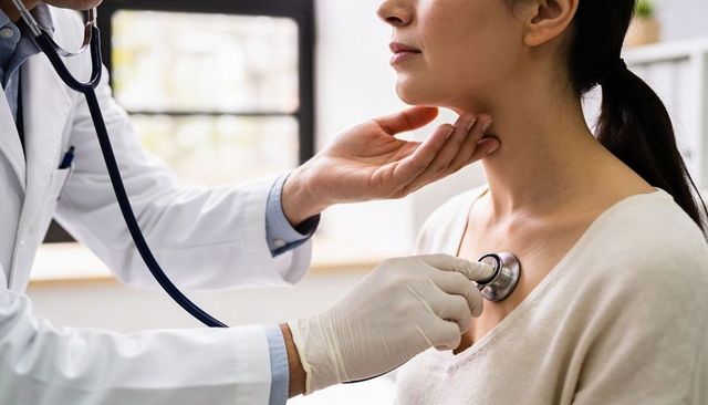 Doctor examining female patient with stethoscope during routine medical checkup