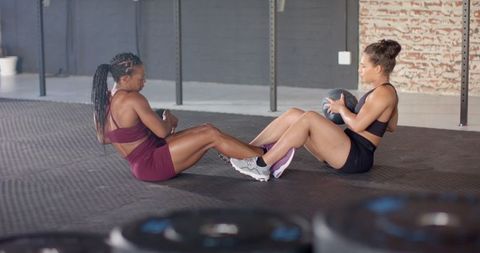 Two Women Doing Sit-Ups Together in Gym Fostering Teamwork and Fitness - Download Free Stock Images Pikwizard.com