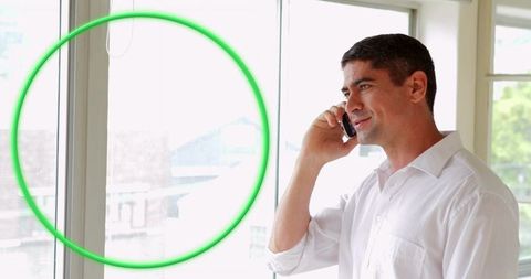 Professional man speaking on smartphone near large window