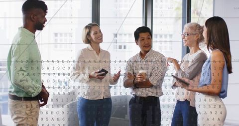 Diverse team collaborating in modern office, holding coffee and devices with code overlay