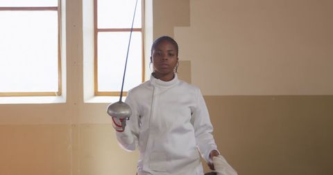 Focused Biracial Female Fencer Holding Epee in Gym