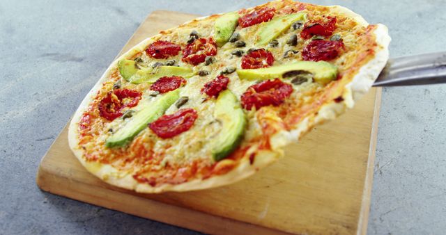 A colorful, freshly baked avocado and sun-dried tomato pizza entices food lovers. - Download Free Stock Photos Pikwizard.com