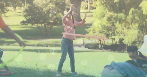 Children enjoying hula hooping on sunny park lawn