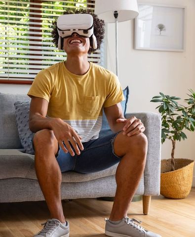 Laughing man wearing vr headset sitting and enjoying immersive home gaming experience