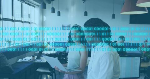 Coworkers Collaborating Over Laptop with Binary Data Overlay in Modern Open-Plan Office