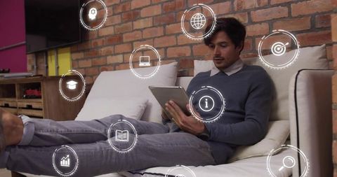 Man on couch using tablet with floating digital icons representing apps data connectivity