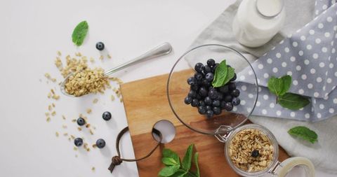 Blueberry Breakfast Bowl on Wooden Board with Granola, Milk and Fresh Mint for Morning