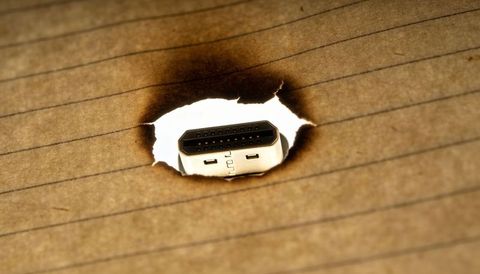 Charred paper revealing hdmi connector macro close-up symbolizing tech connectivity contrast