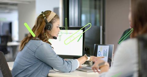 Call Center Agent pointing at laptop charts during team collaboration in modern open office