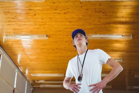 Confident teen athlete posing with stopwatch in gymnasium