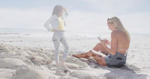 Double exposure beach lifestyle woman using smartphone, friend standing on rocky shore