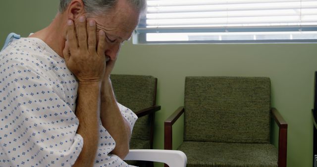 Elderly man sitting in a hospital waiting area, expressing worry and distress. This image is useful for articles and publications focused on healthcare issues, mental health among seniors, hospital experiences, patient stories, and elderly care.