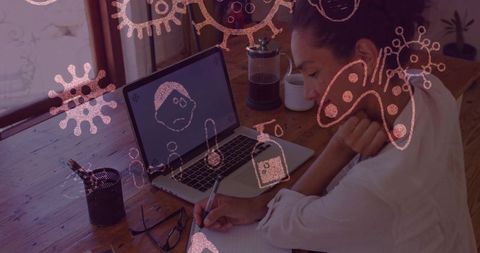 Focused mature woman writing in home office with virus graphics overlay