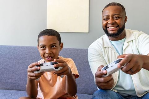 African american father and son playing video games on couch sharing joyful family bond