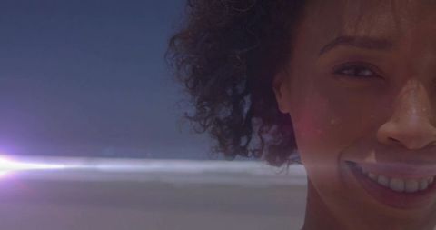 Joyful woman with natural curls enjoying sunny beach day