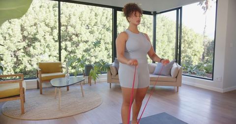 Woman Exercising with Resistance Band in Bright Modern Living Room