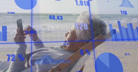 Senior woman reclining on beach chair using smartphone viewing digital data overlays
