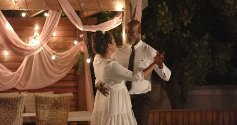 Romantic dance under string lights at intimate wedding party