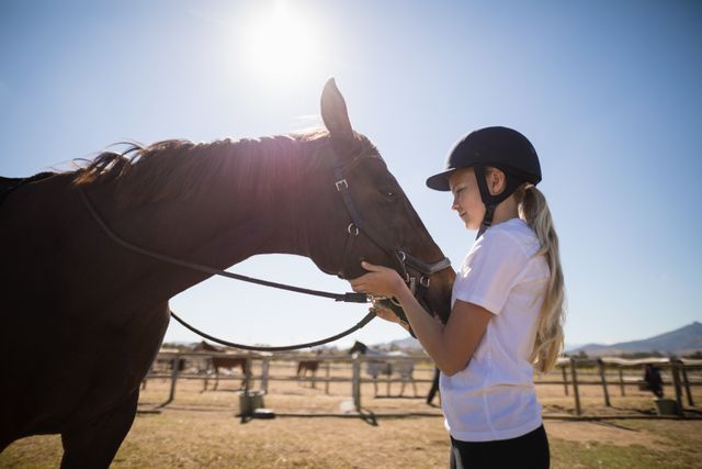 Rider girl caressing a horse in the ranch on a sunny day