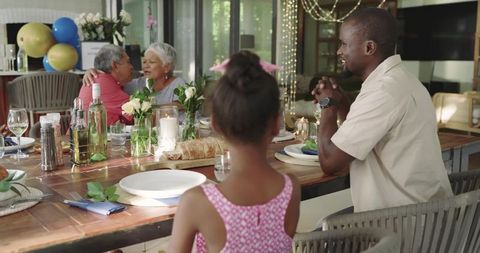 Multigenerational family sharing candlelit patio dinner with balloons, floral centerpiece
