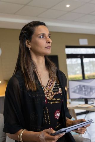 Indian businesswoman holding tablet reviewing 3d architectural rendering in modern office