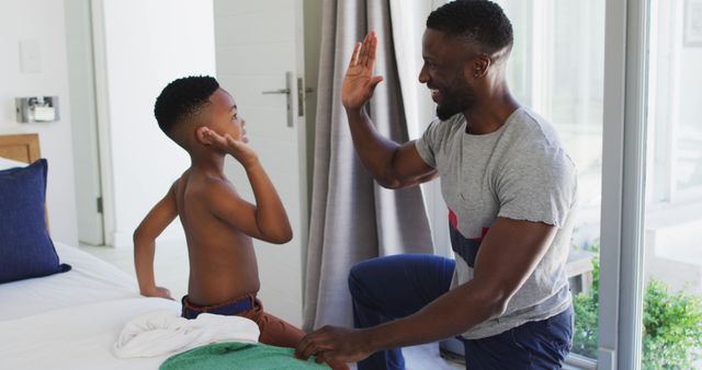African american father helping his son with getting dressed in bedroom - Download Free Stock Photos Pikwizard.com