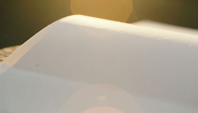Glowing glossy white curved surface catching warm sunlight with amber lens flare