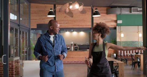 Friendly coffee shop interaction between customer and barista laughing and dancing