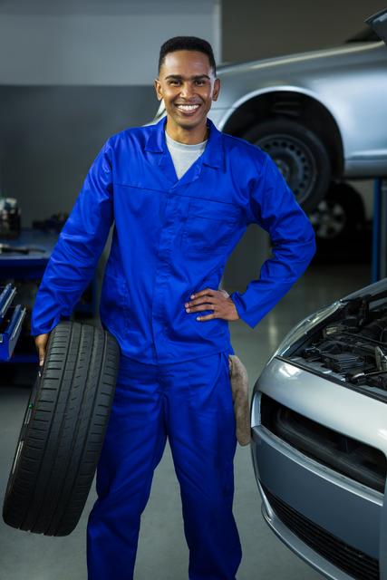 Smiling Mechanic Holding Tire in Auto Repair Garage - Download Free Stock Images Pikwizard.com