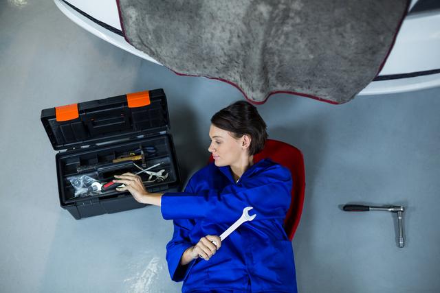 Female mechanic removing tool from tool box in repair garage