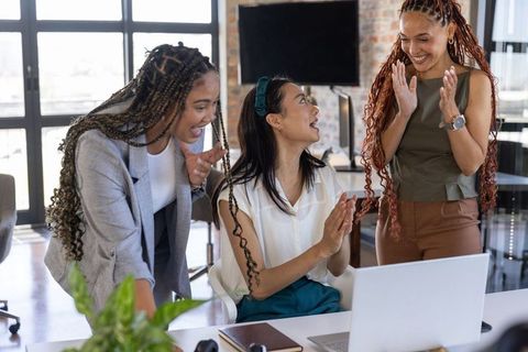 Diverse female team celebrating success in office environment