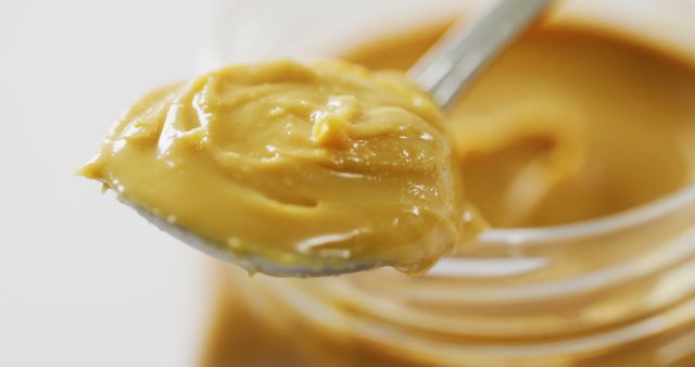 Close-up of Smooth Peanut Butter on Spoon Against Jar - Download Free Stock Images Pikwizard.com