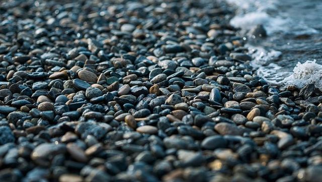 Glinting wet pebble beach with foamy waves lapping shoreline