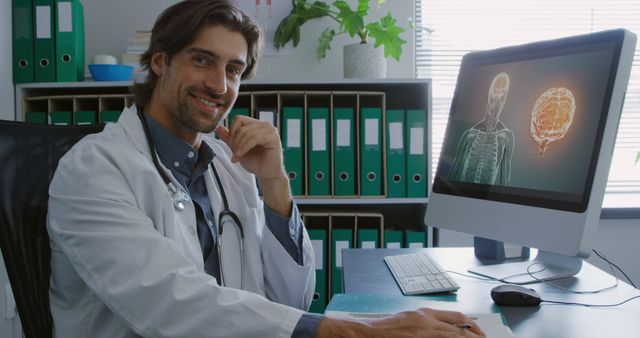 Smiling Doctor Sitting at Desk with Medical Display on Computer - Download Free Stock Images Pikwizard.com