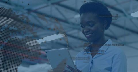 Smiling woman using tablet in industrial warehouse with digital globe and data overlay
