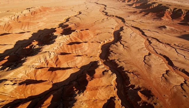 Aerial view of eroded sandstone plateau with meandering dry channels and deep canyons