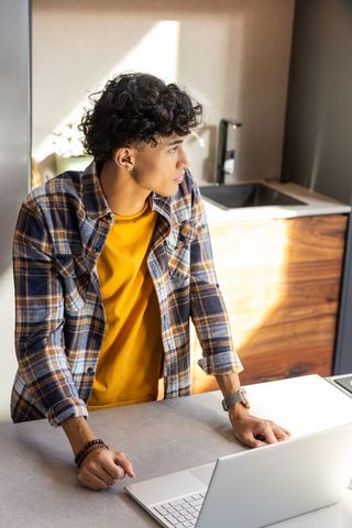 Young Man Working on Laptop at Sunlit Countertop in Modern Space