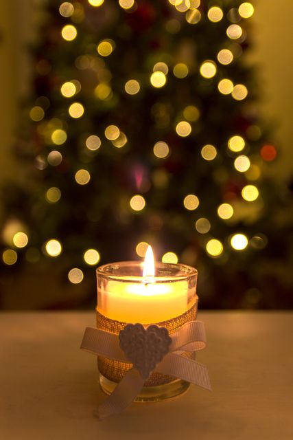 Depicts warm, festive ambiance with glowing candle and Christmas decorations. Perfect for seasonal greetings, holiday event promotions, festive advertisements, and creating cozy setting.