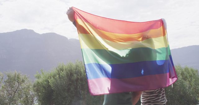 Happy diverse male couple holding lgbt flag with arms wide - Download Free Stock Photos Pikwizard.com