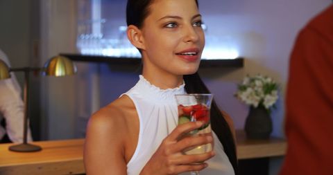 Young Woman Savoring Refreshing Drink in Social Setting