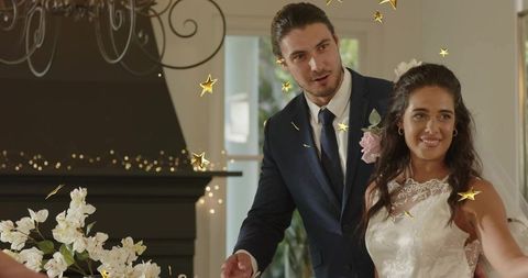 Elegant bride and groom celebrating at reception with gold star confetti and chandelier glow