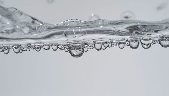 Macro water surface showing hanging bubbles and crystal-clear liquid interface