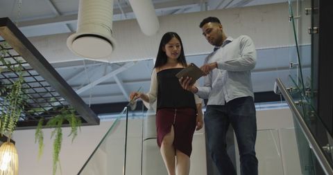 Colleagues Collaborating on Stairs with Tablet in Modern Office