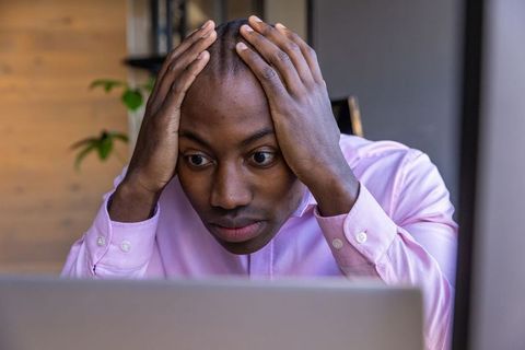 Frustrated Man Holding Head Looking at Laptop Screen