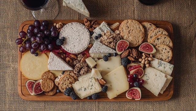 Showcasing rustic charcuterie board overflowing with artisanal cheeses, figs, grapes and wine