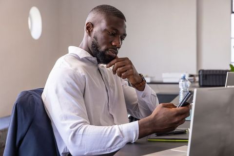 Focused professional analyzing smartphone in contemporary office