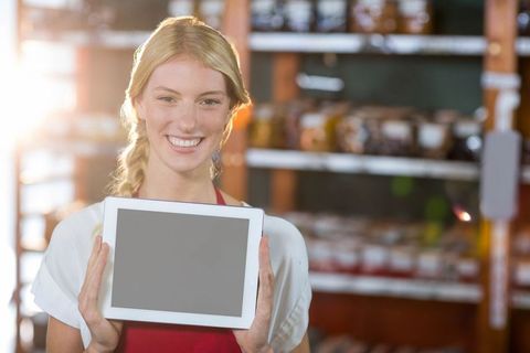 Smiling Shop Assistant Holding Tablet in Bakery